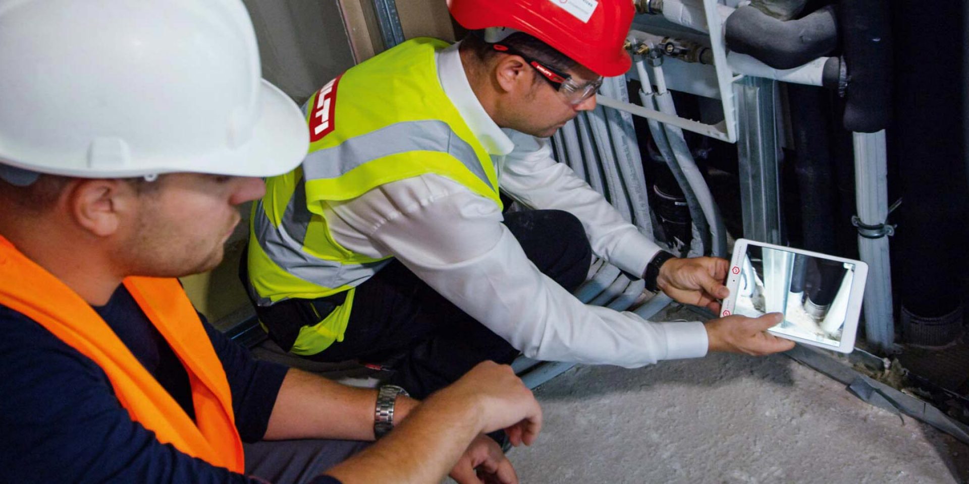 Bauarbeiter die gerade mit einem Tablet die eingebauten Brandschutzvorrichtungen dokumentieren