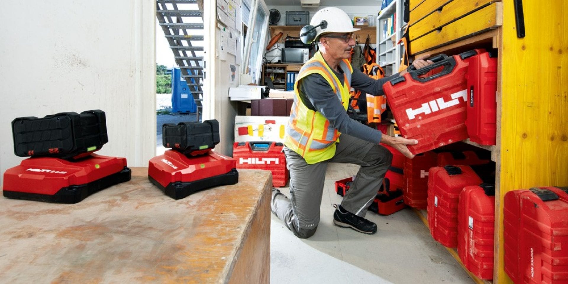 Image de la personne avec une mallette Hilti dans un dépôt d'outils.