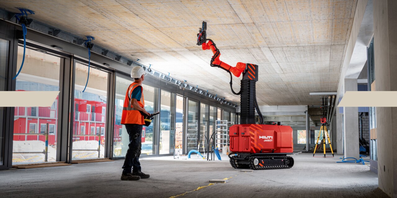 Un homme demande au Hilti Jaibot de travailler au plafond en le faisant fonctionner via une télécommande.