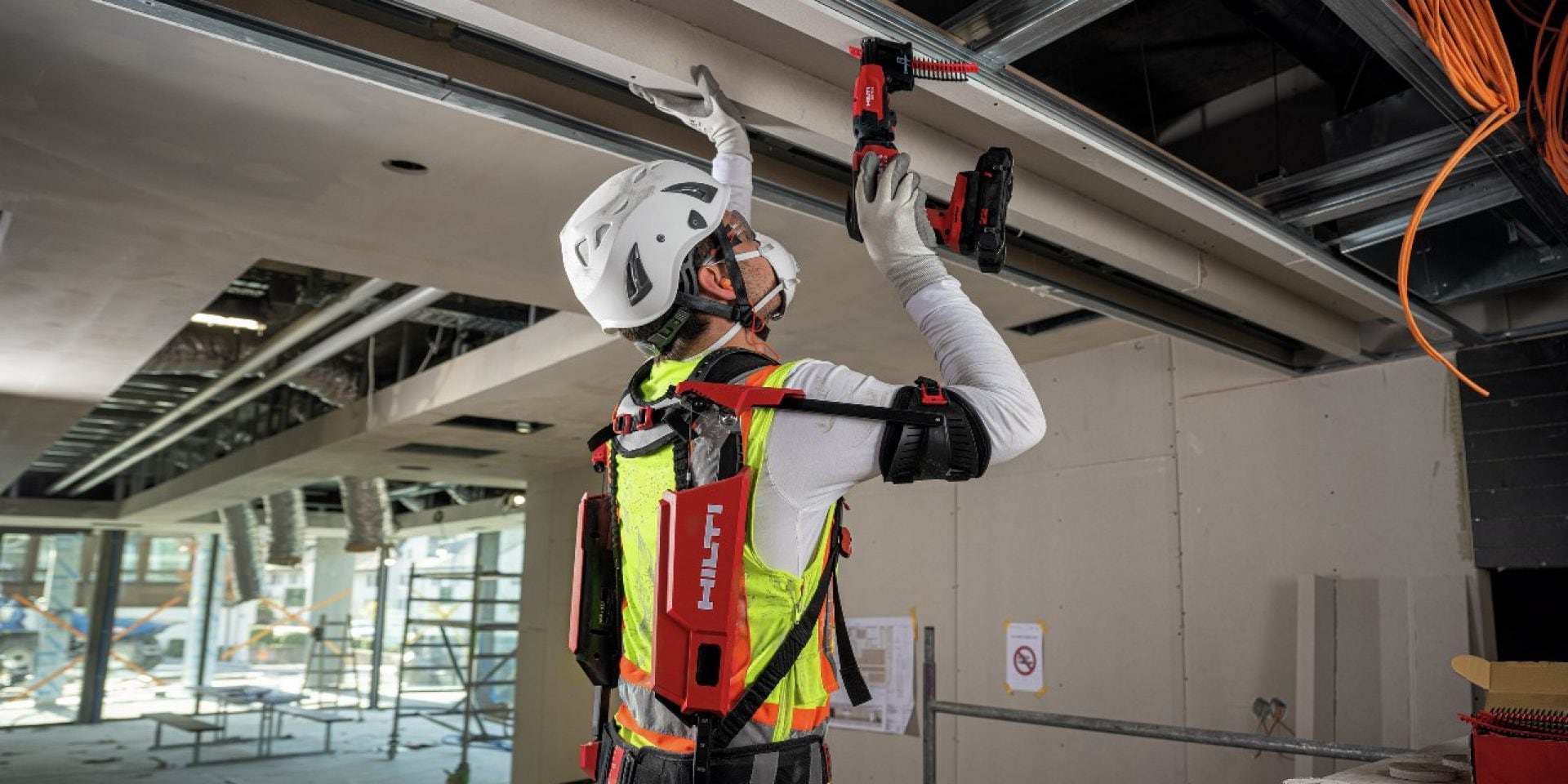 Une personne réalise des travaux au plafond avec l'exosquelette Hilti.