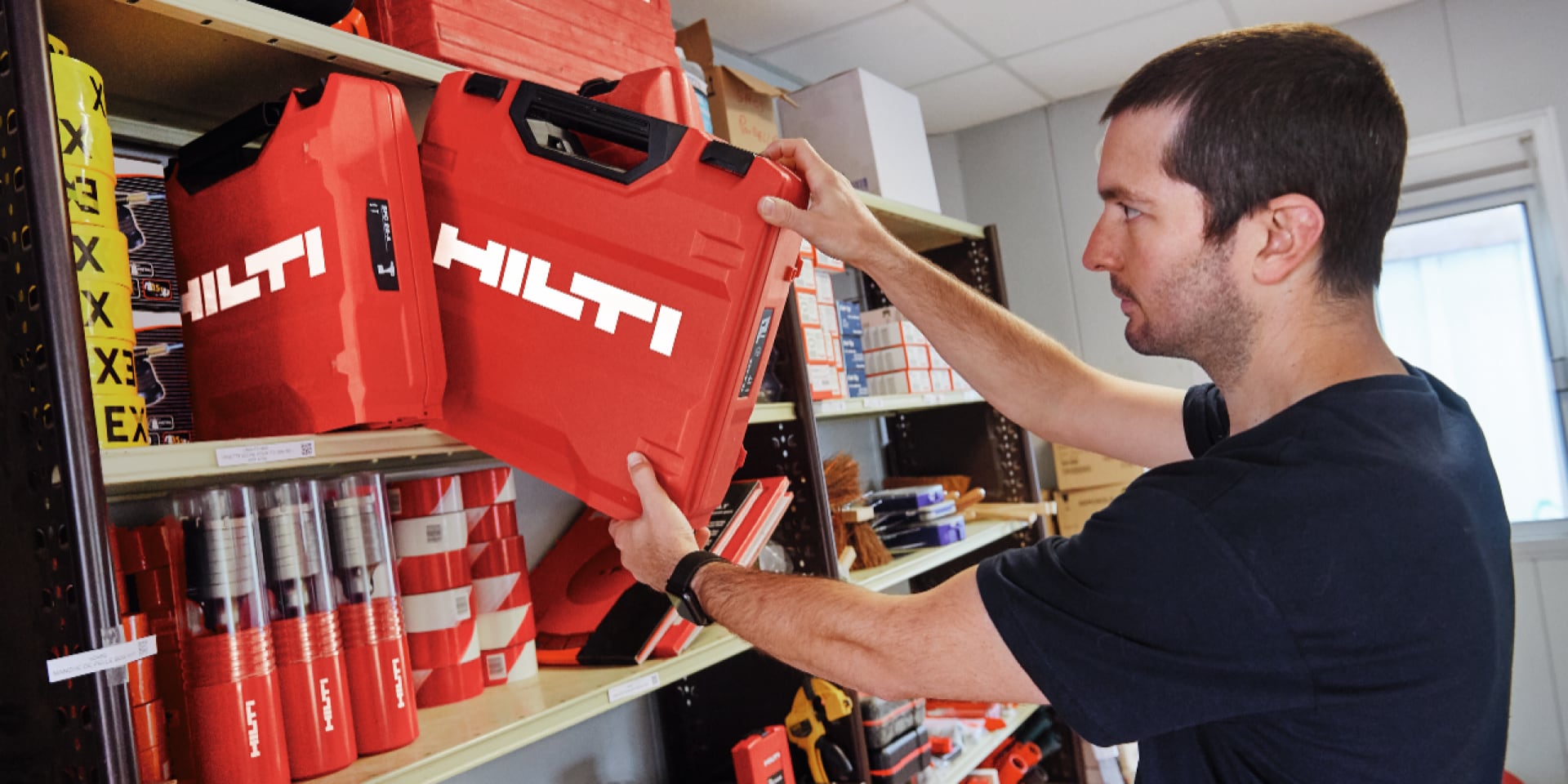 Une personne glisse un coffret dans une étagère.
