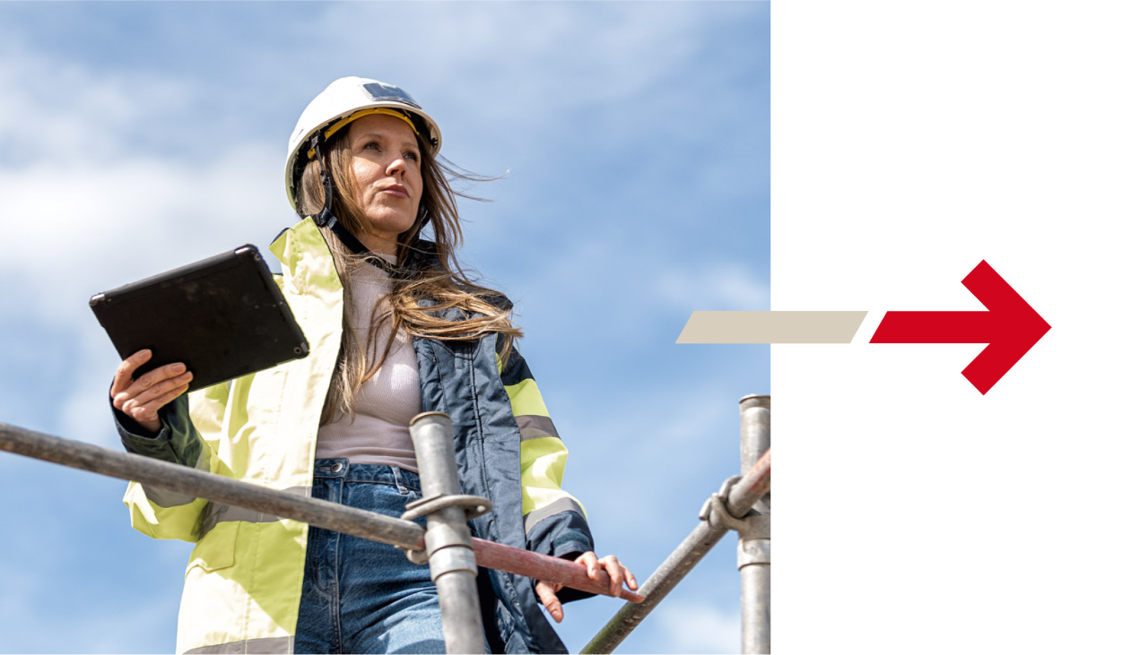Una donna che indossa abiti da cantiere e tiene in mano un tablet guarda in lontananza. Alla sua destra su sfondo bianco c'è una freccia rossa che punta verso destra.