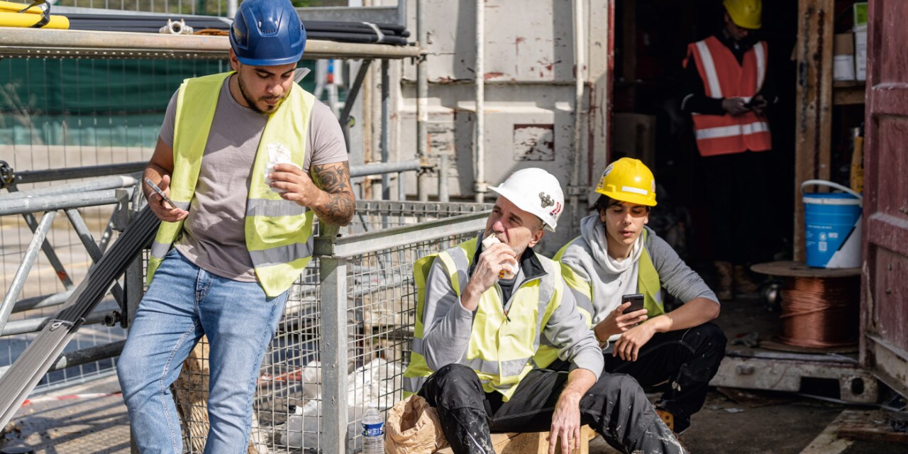 Inquadratura di tre operai edili che si prendono una pausa in un cantiere edile.